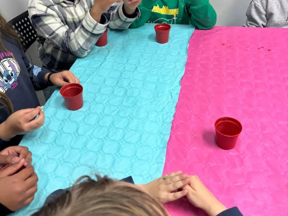 Crianças sentadas à mesa numa atividade de expressão plástica no centro