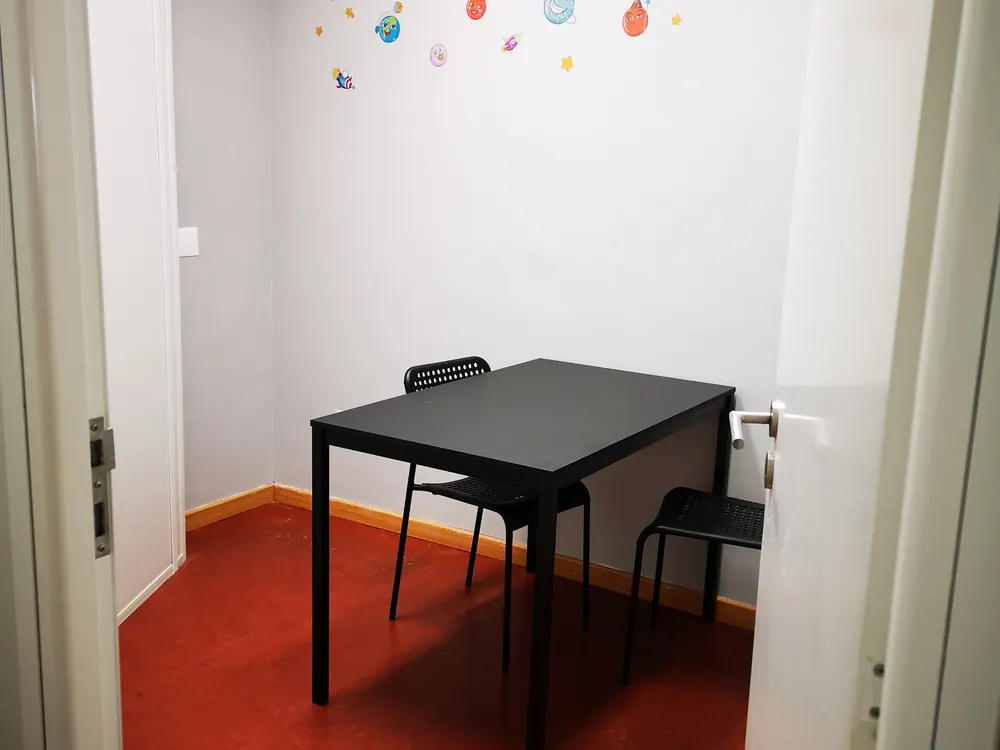 Sala pequena de explicações individuais, com mesa, cadeiras e autocolantes de planetas na parede